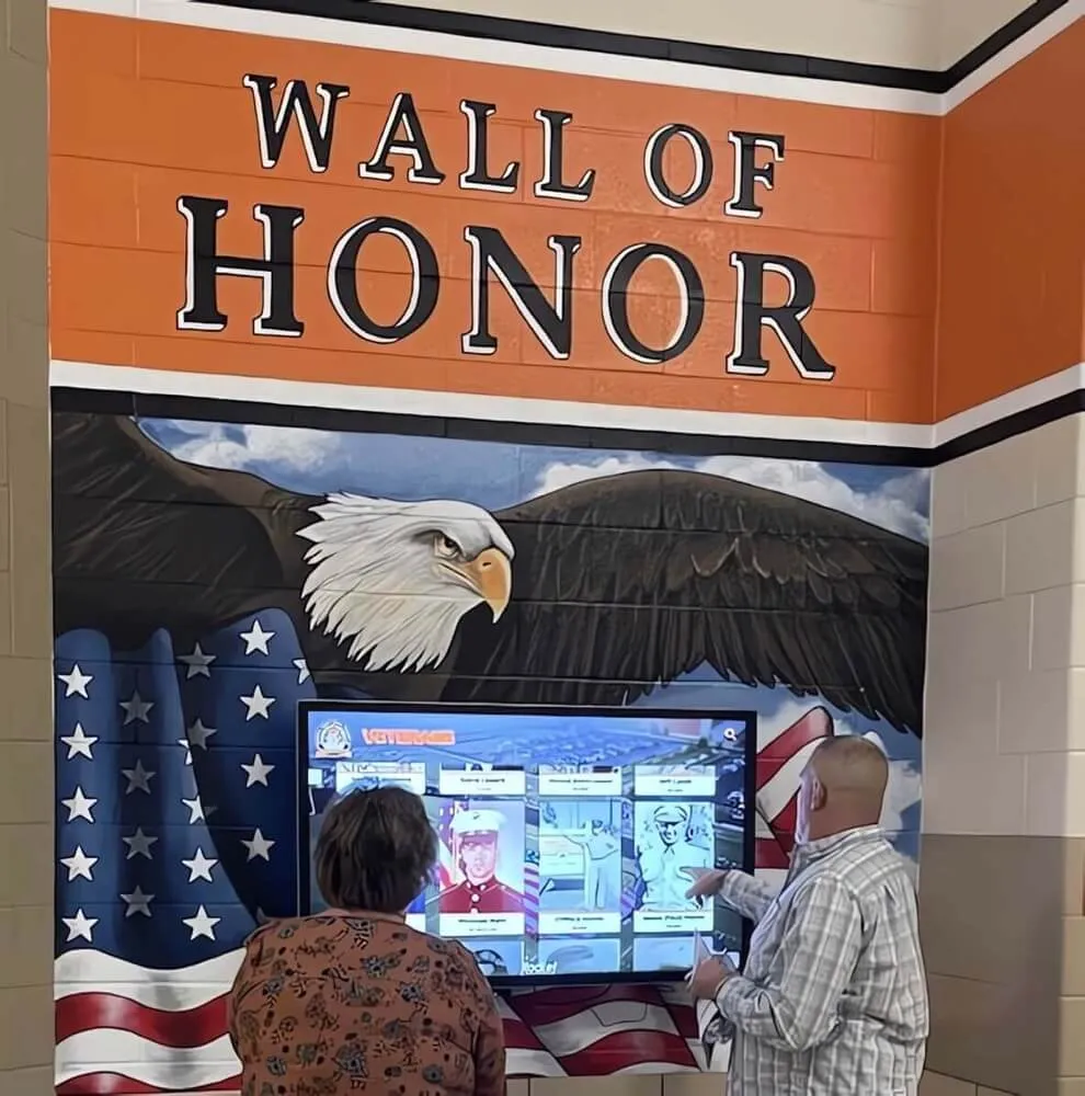 Visitors engaging with wall of honor interactive touchscreen display